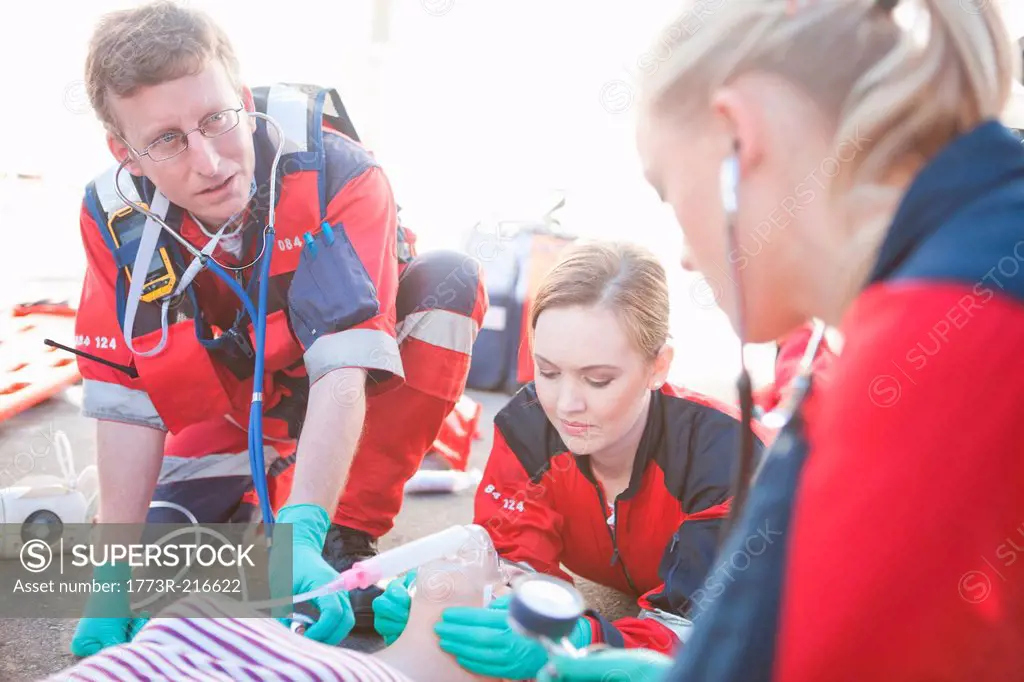 Group of paramedics tending patient on road