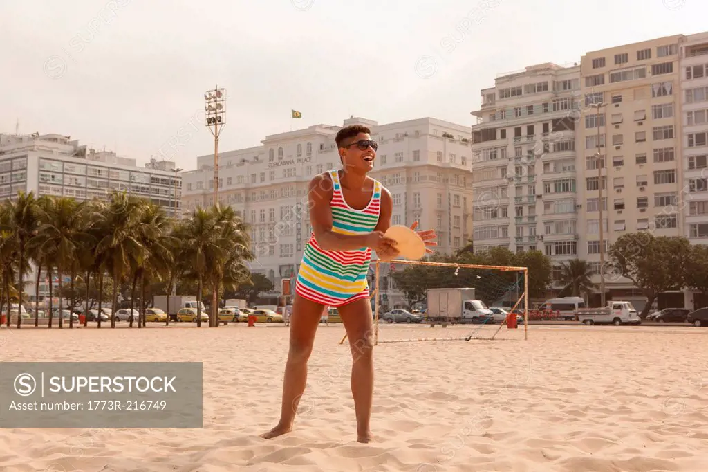 Young man about to hit ball with bat on Copacabana Beach, Rio de Janeiro, Brazil