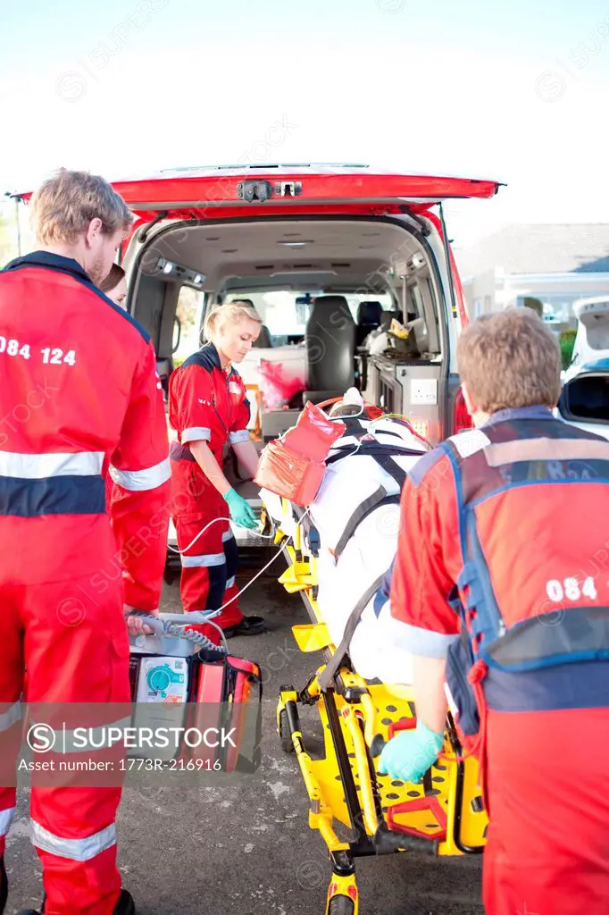 Paramedics lifting woman on stretcher into ambulance