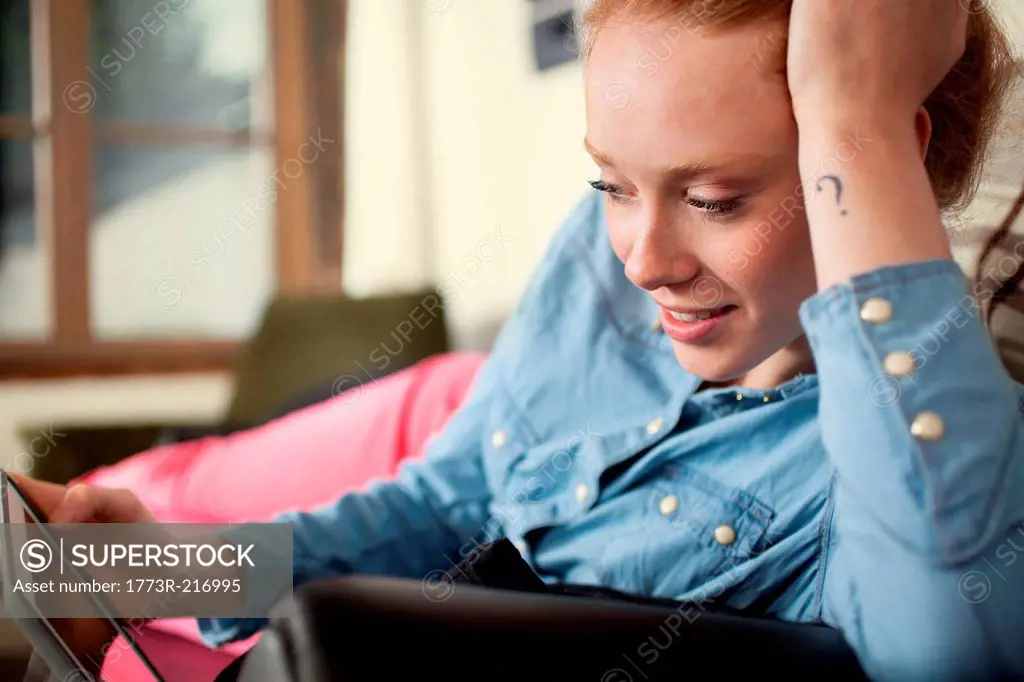 Young woman with question mark tattoo using digital tablet