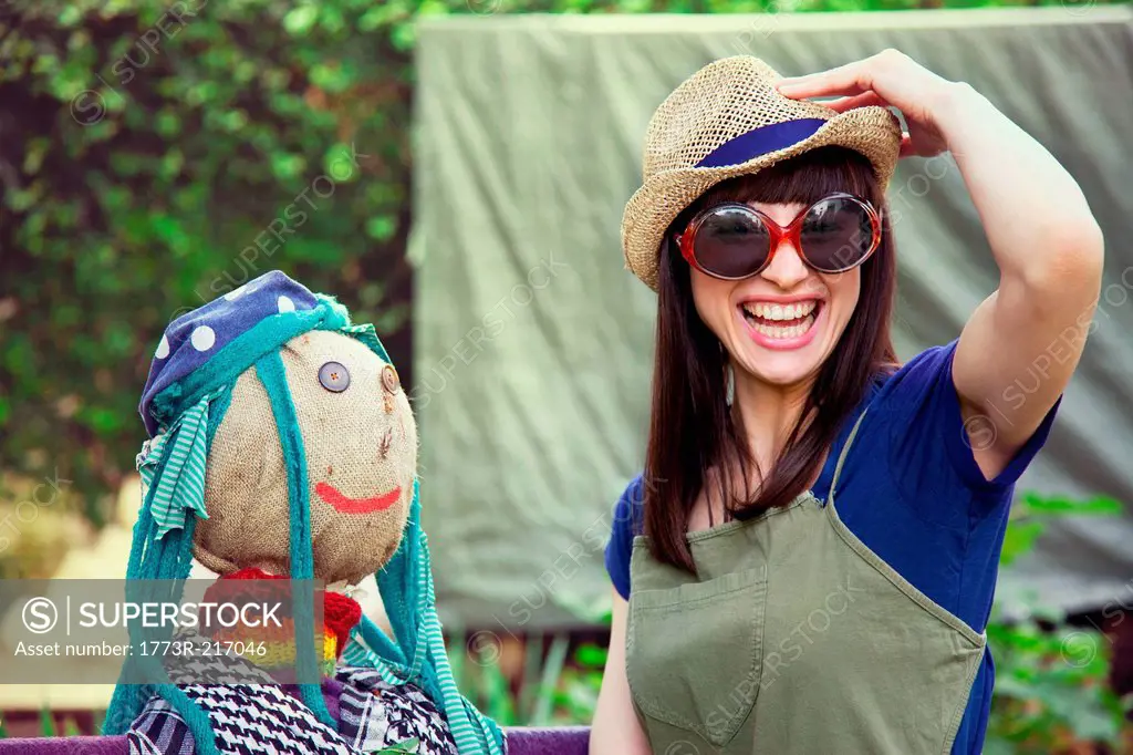Woman wearing sunglasses and hat with scarecrow