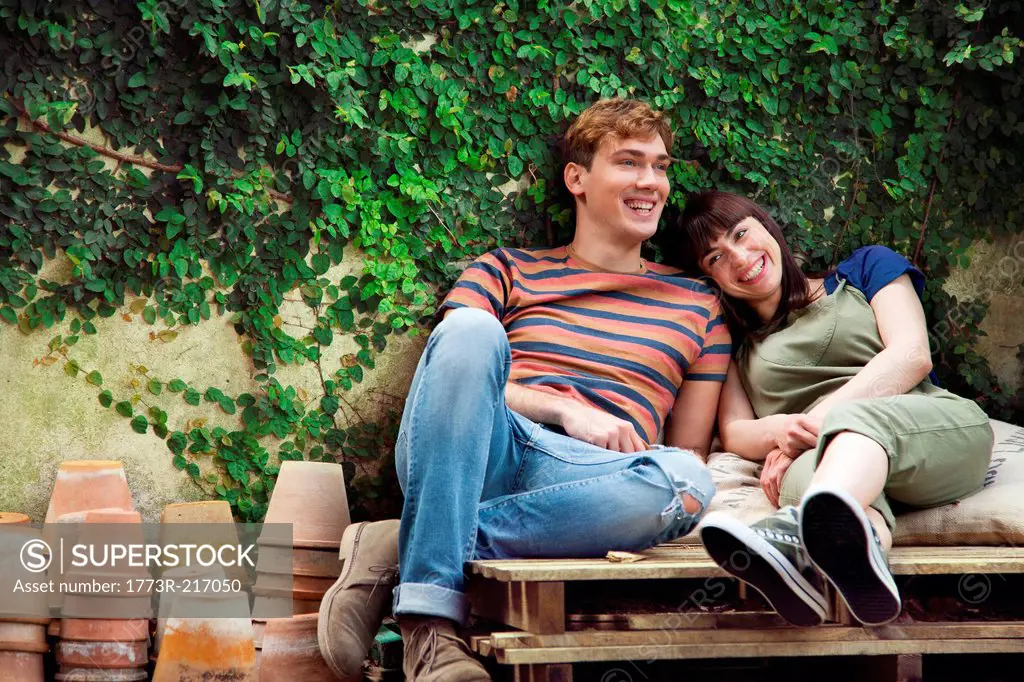 Couple sitting on wooden palettes with plant pots