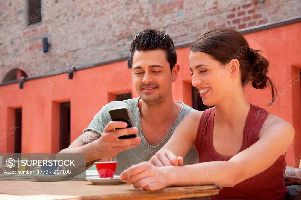 Couple using smartphone outside cafe, Florence, Tuscany, Italy