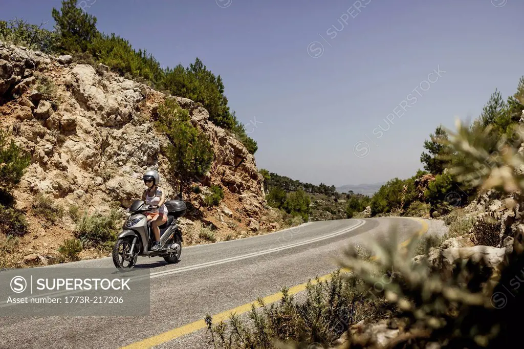 Woman riding moped along mountain road in Samos, Greece