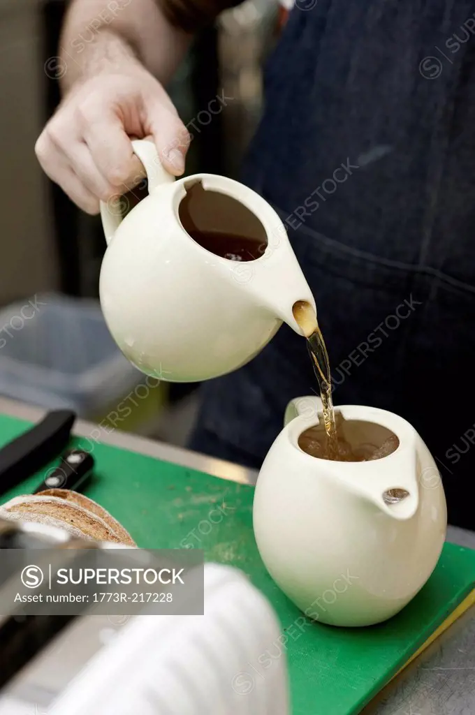 Barista pouring tea into teapot with ice