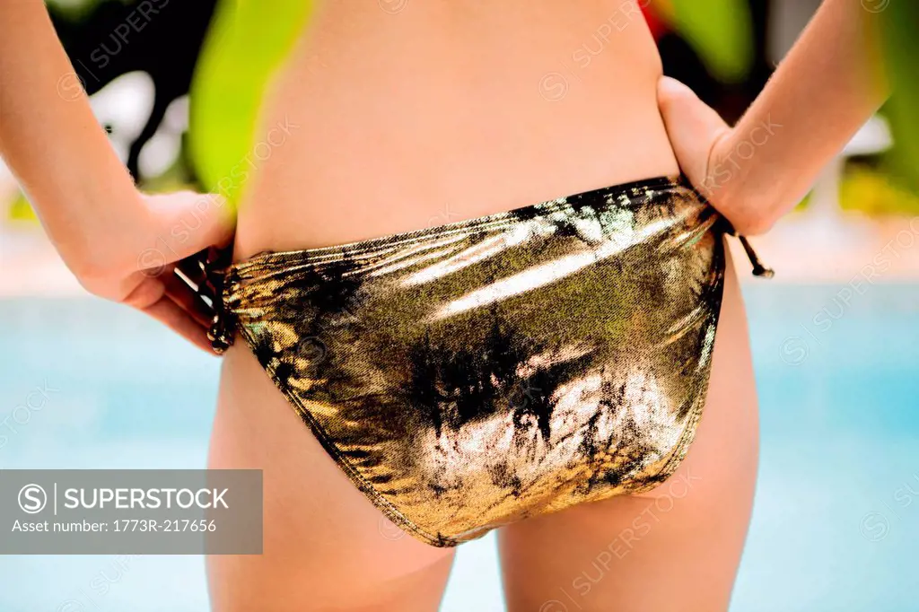 Close up portrait of female buttocks wearing gold bikini bottoms