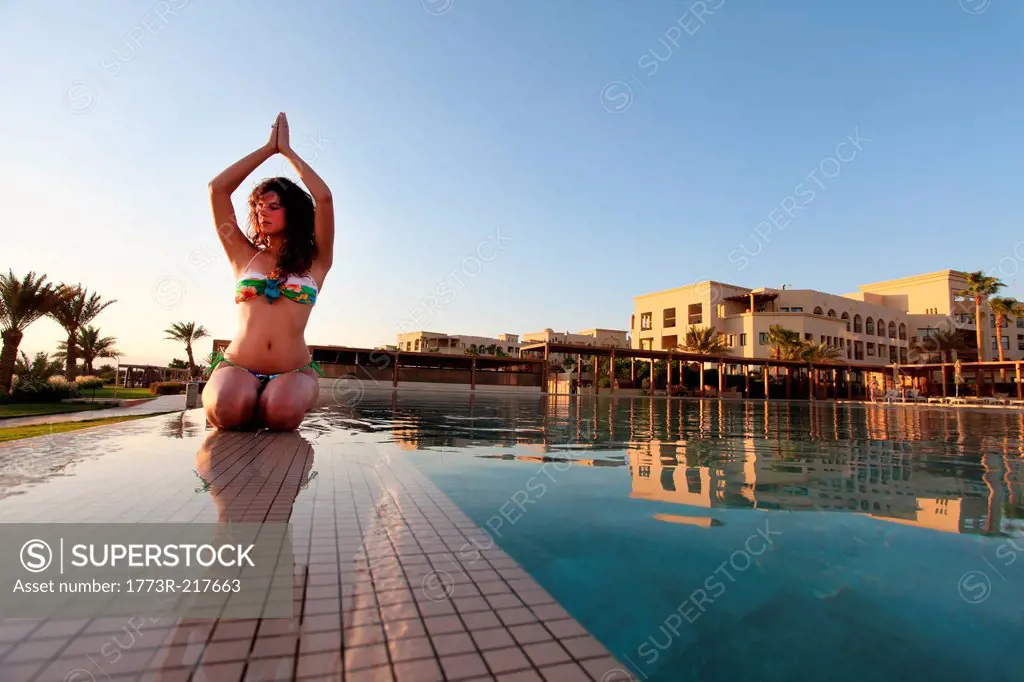 Woman practicing yoga poolside, Aqaba, Tala Bay, Jordan