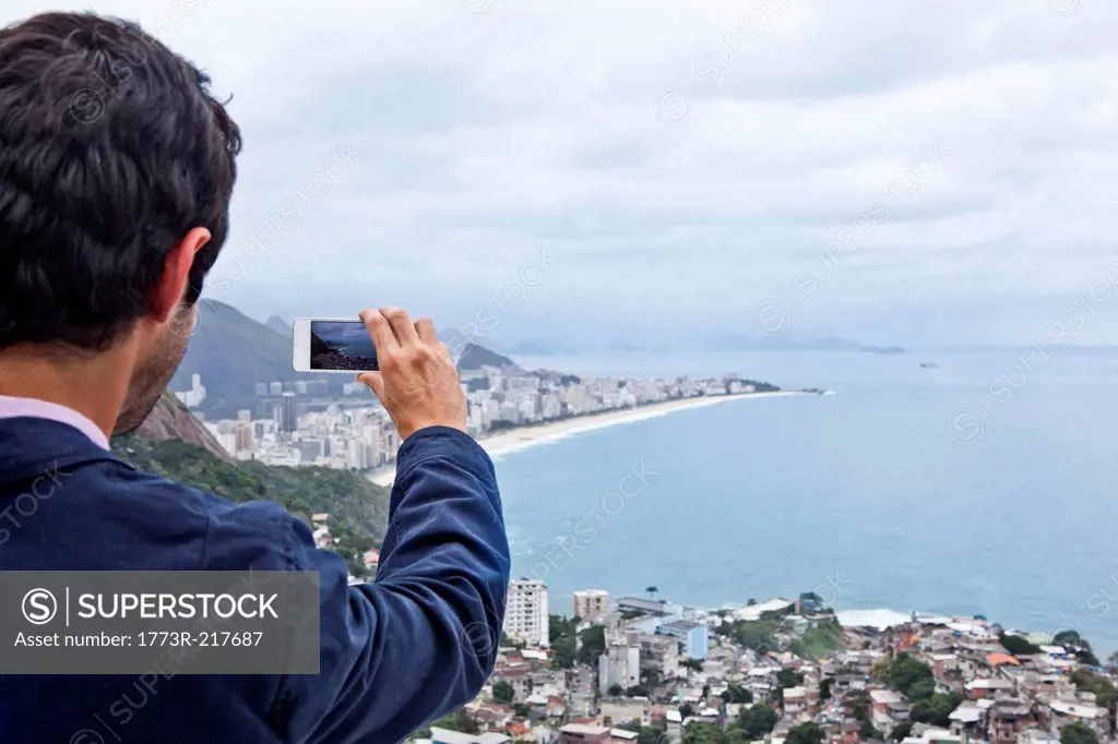 Young man photographing with mobile phone, Casa Alto Vidigal, Rio De Janeiro, Brazil