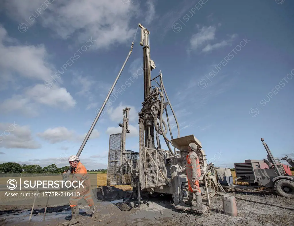 Workers operating drilling rig to explore for coal in field