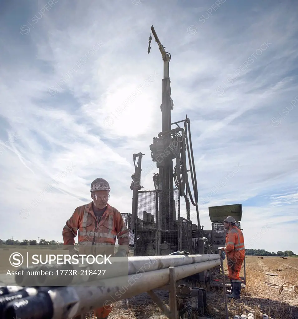 Workers operating drilling rig in field