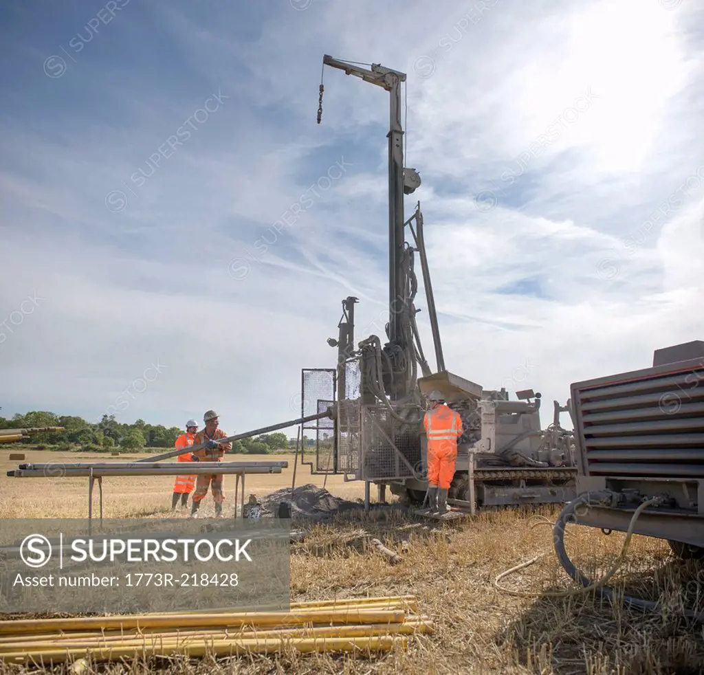 Small team of workers operating drilling rig in field