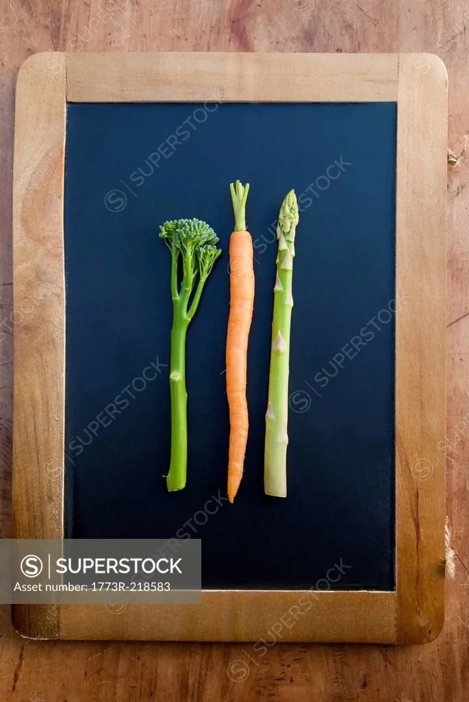 Carrot, broccoli and asparagus on blackboard, still life