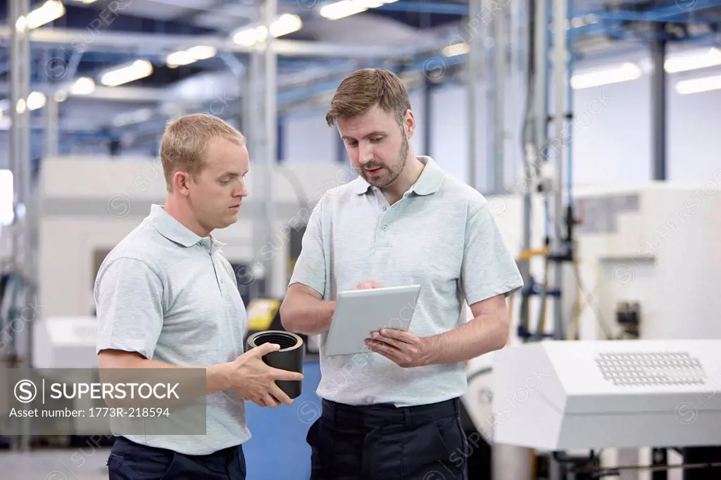 Two workers looking at digital tablet in engineering warehouse