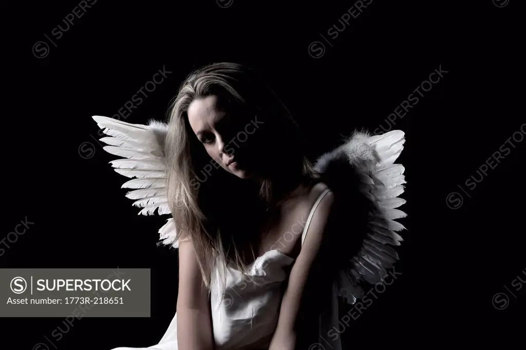 Studio portrait of sad woman wearing angel wings
