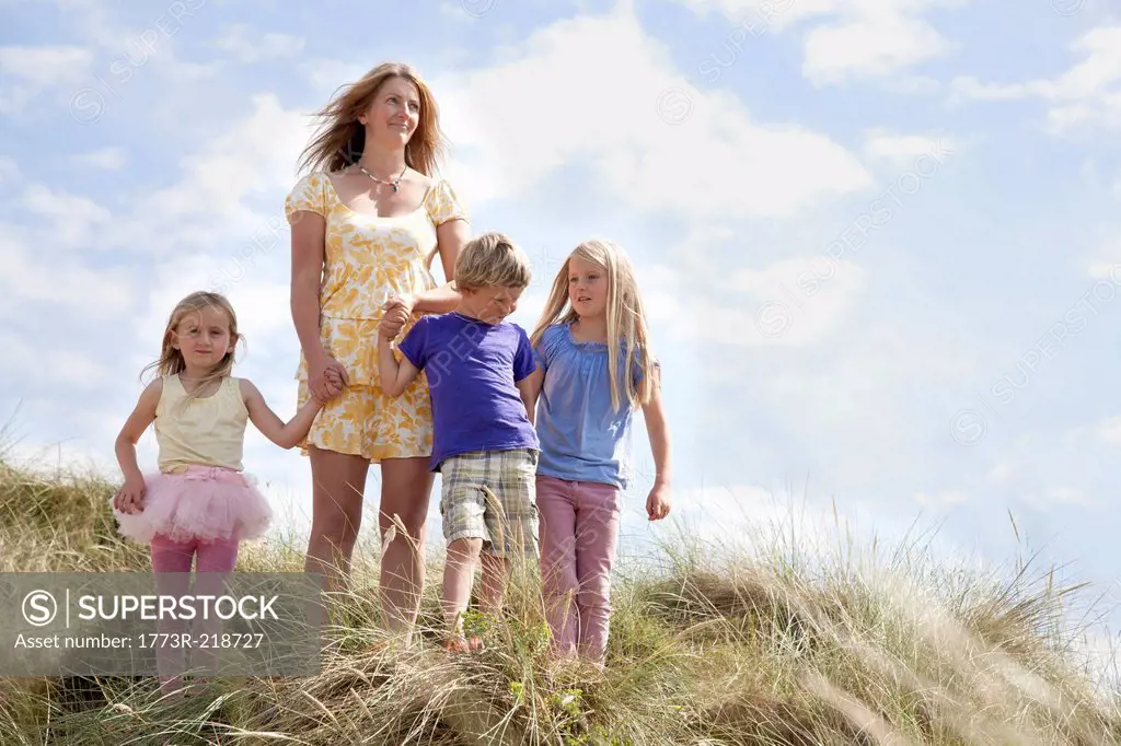 Mother with three children on dunes, Wales, UK