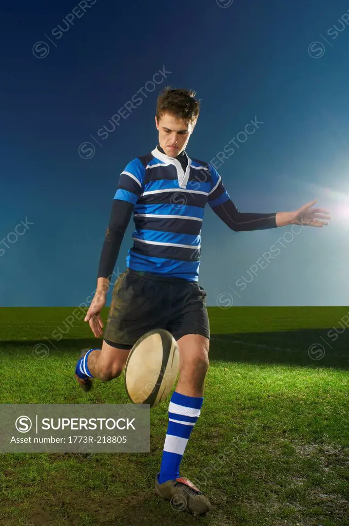 Portrait of young man kicking rugby ball