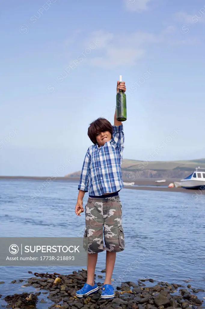 Boy holding message in a bottle at seaside