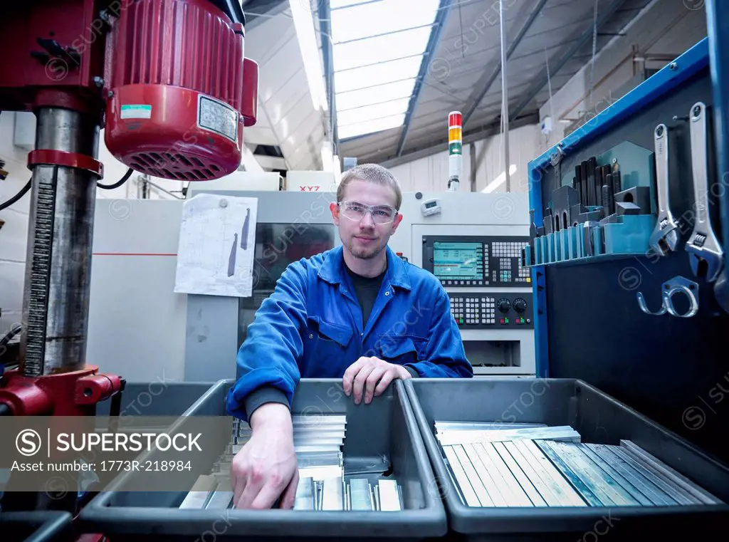 Apprentice engineer with components in factory, portrait