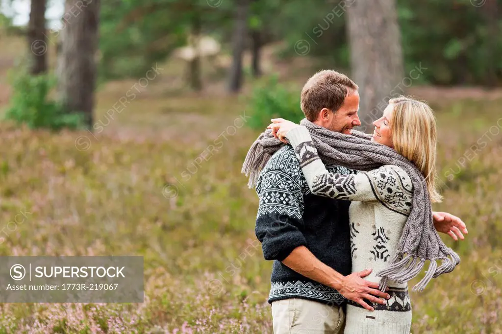 Mid adult couple wrapped in scarf hugging