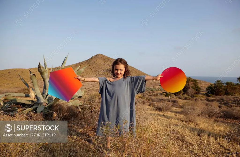 Girl holding bright shapes in desert, Cabo de Gata, Almeria, Spain