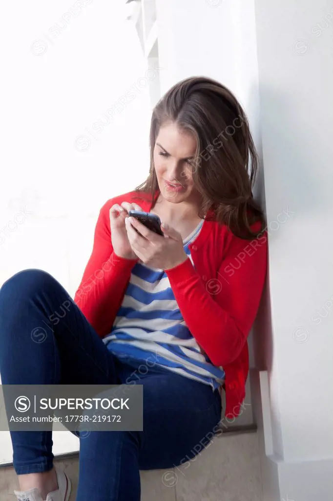 Young woman sitting on step using cell phone