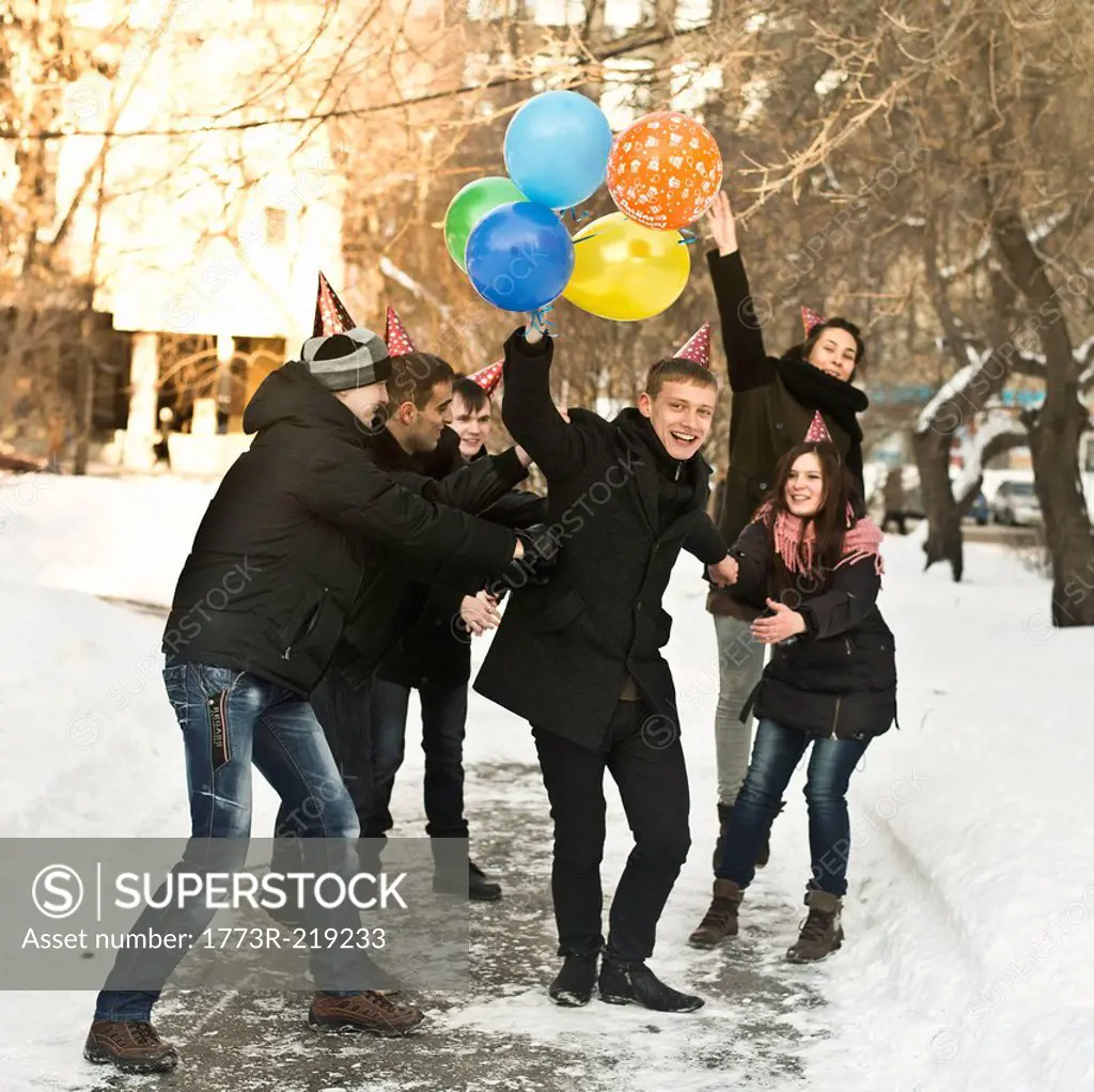 Group of young friends with party hats and balloons