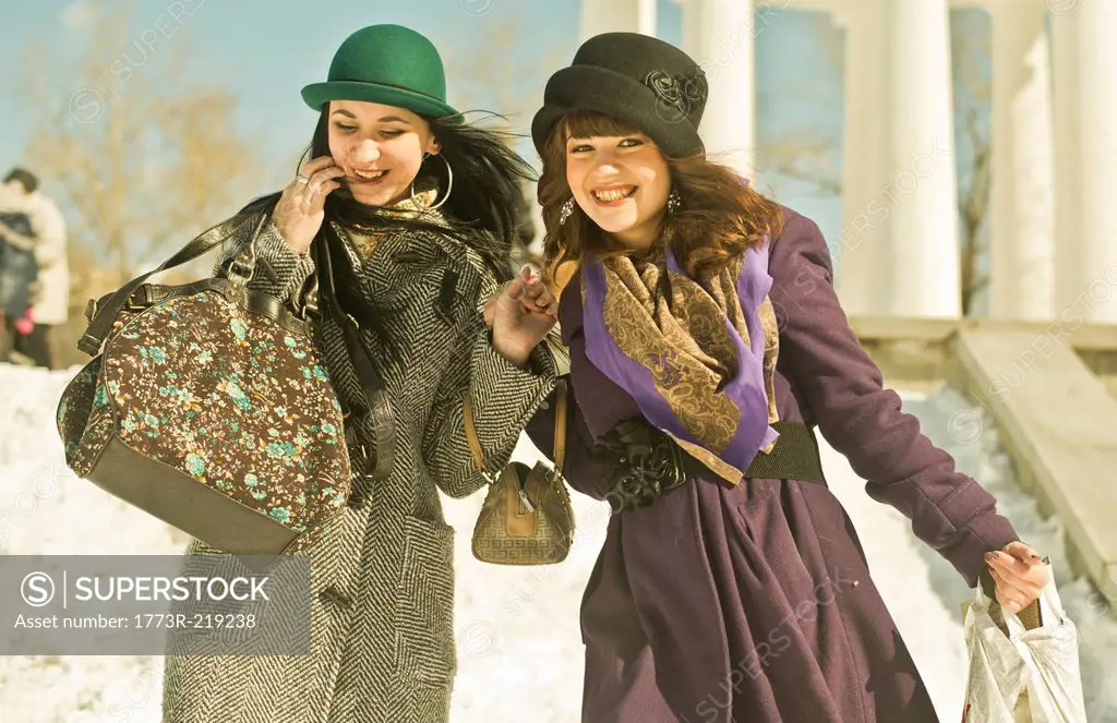 Two young women carrying bags in snow