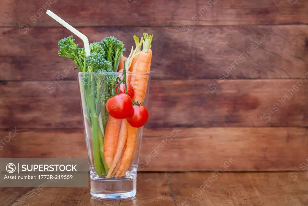 Glass of broccoli, carrots and tomato with straw