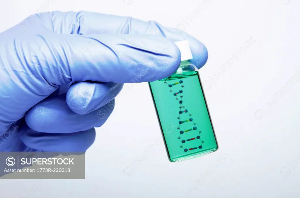 Biology research: hand wearing a nitrile glove is holding a vial with a model of DNA molecule inside