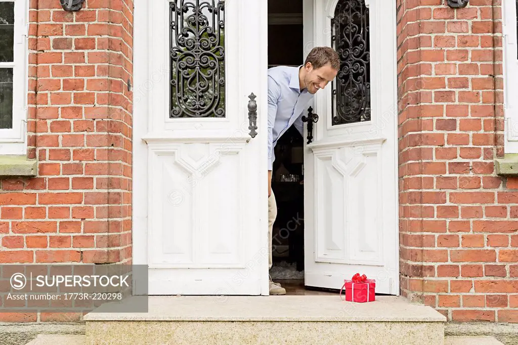 Mid adult man with gift on front doorstep