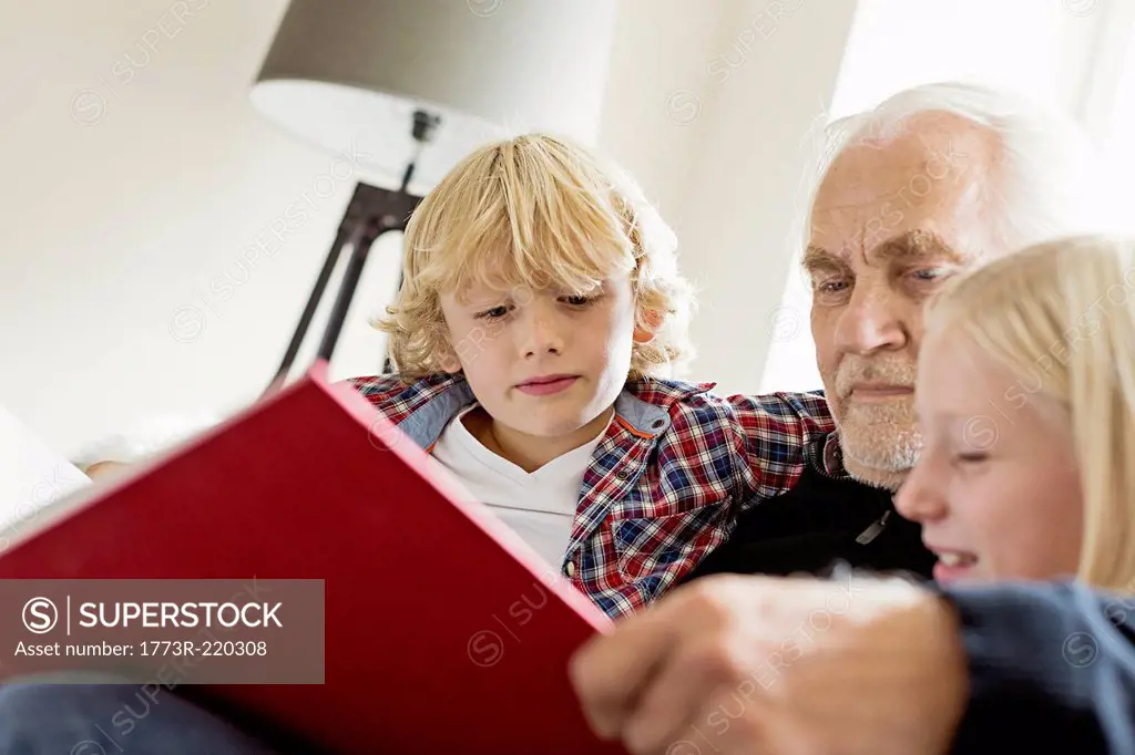 Grandfather reading book to grandchildren
