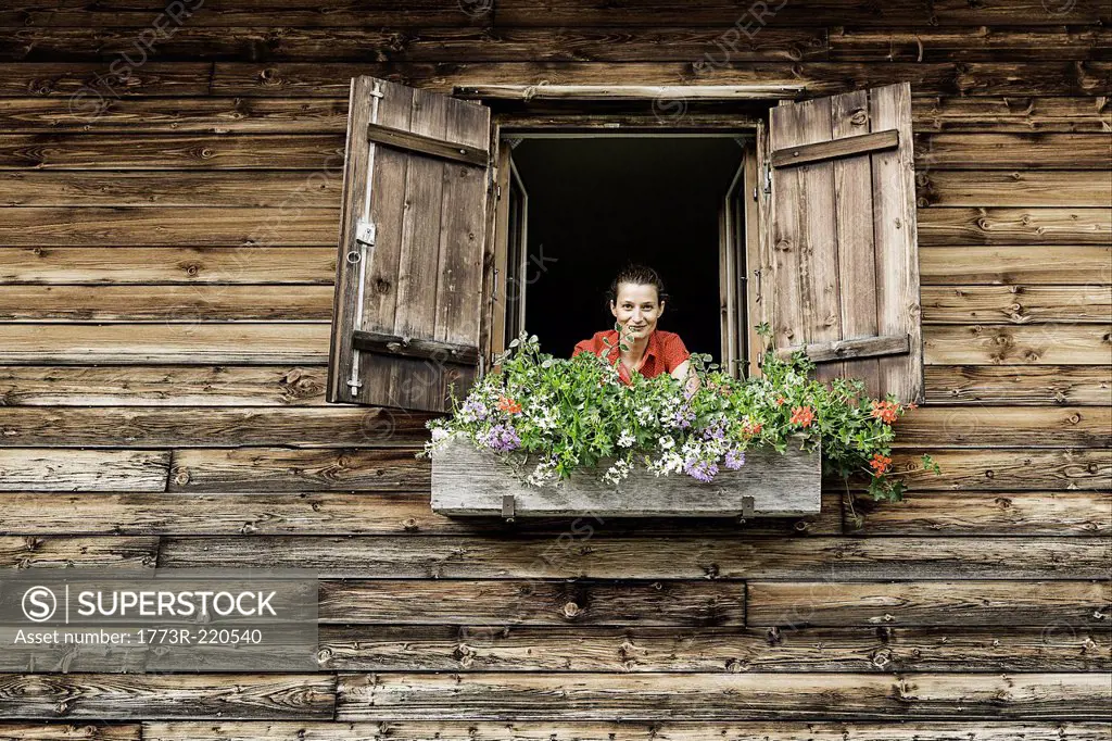 Portrait of mid adult woman at chalet window, Achenkirch, Tyrol, Austria