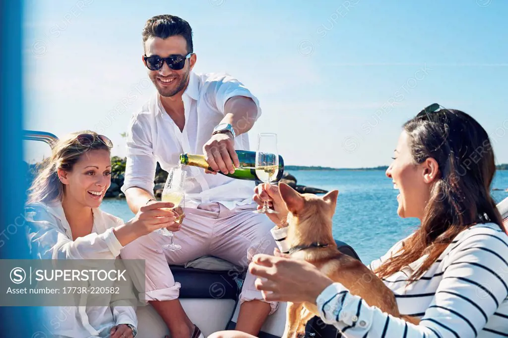 Man pouring champagne for young women on boat, Gavle, Sweden
