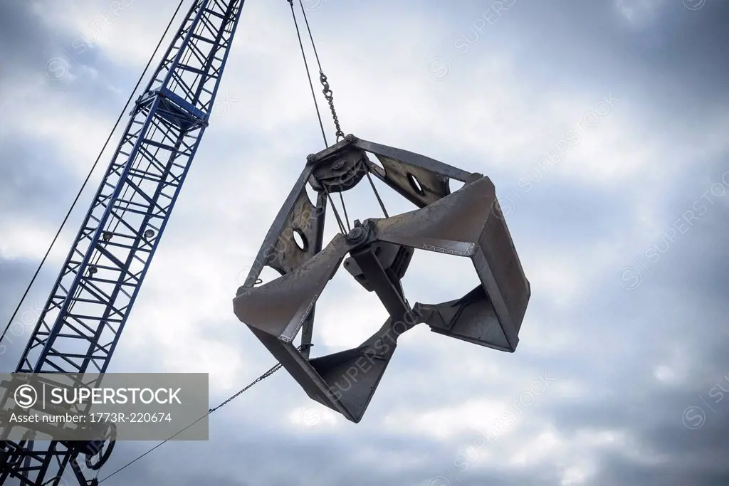 Low angle view of crane grab against cloudy sky