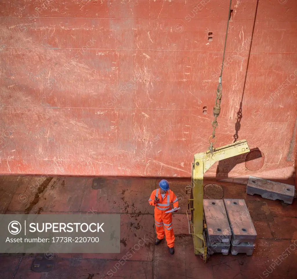 High angle view of worker checking metal alloy ingots in ship's hold