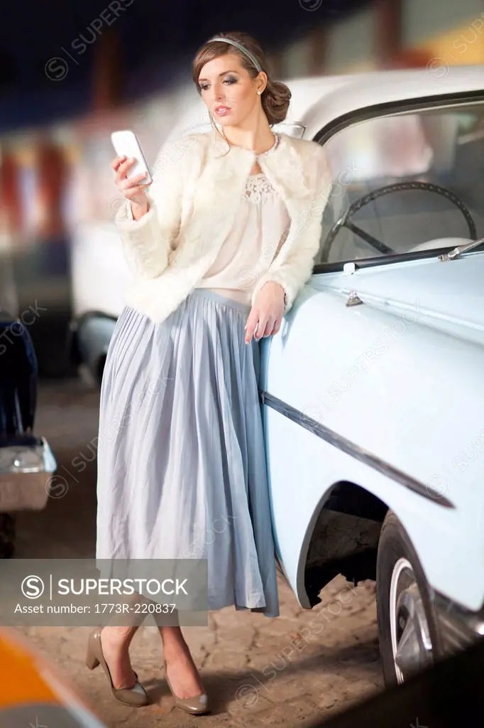 Woman leaning on convertible texting