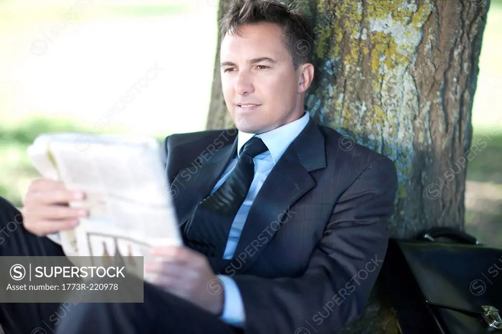 Businessman reading under tree