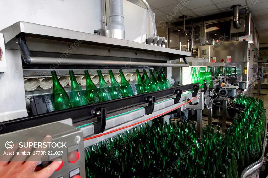 Person operating bottling machine in industrial wine cellar