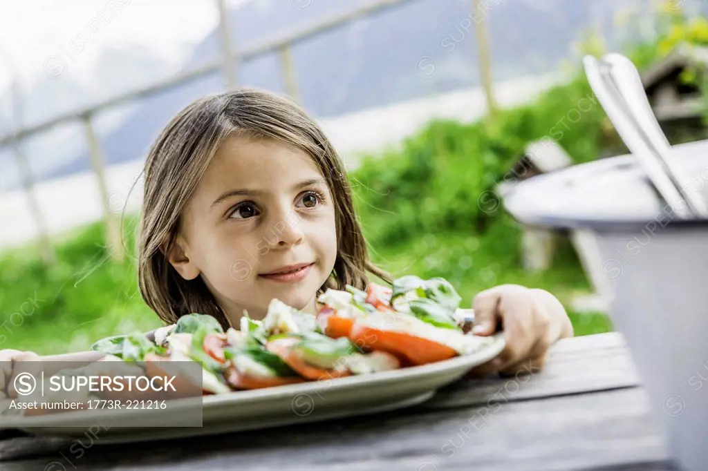 Young girl holding salad plate for picnic lunch, Tyrol, Austria