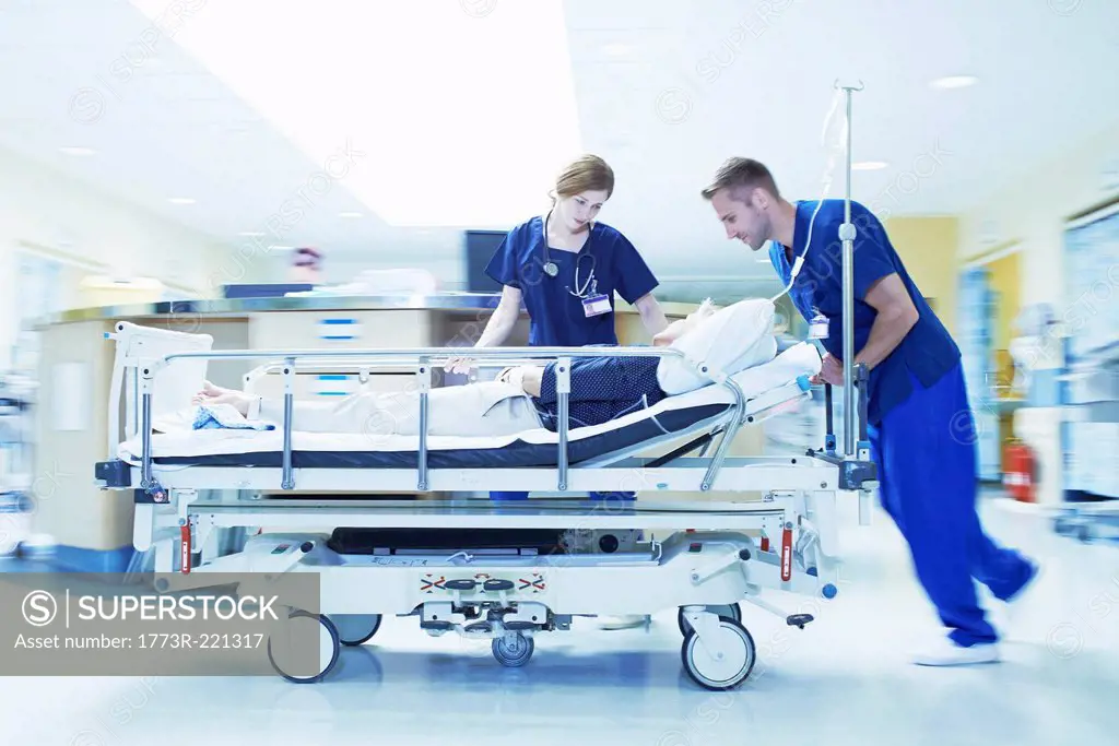 Two medics pushing gurney in hospital emergency room