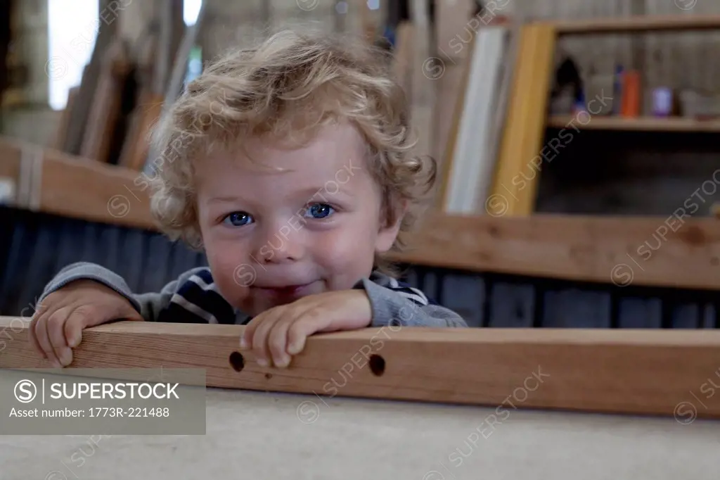 Close up portrait of male toddler inside boat in workshop