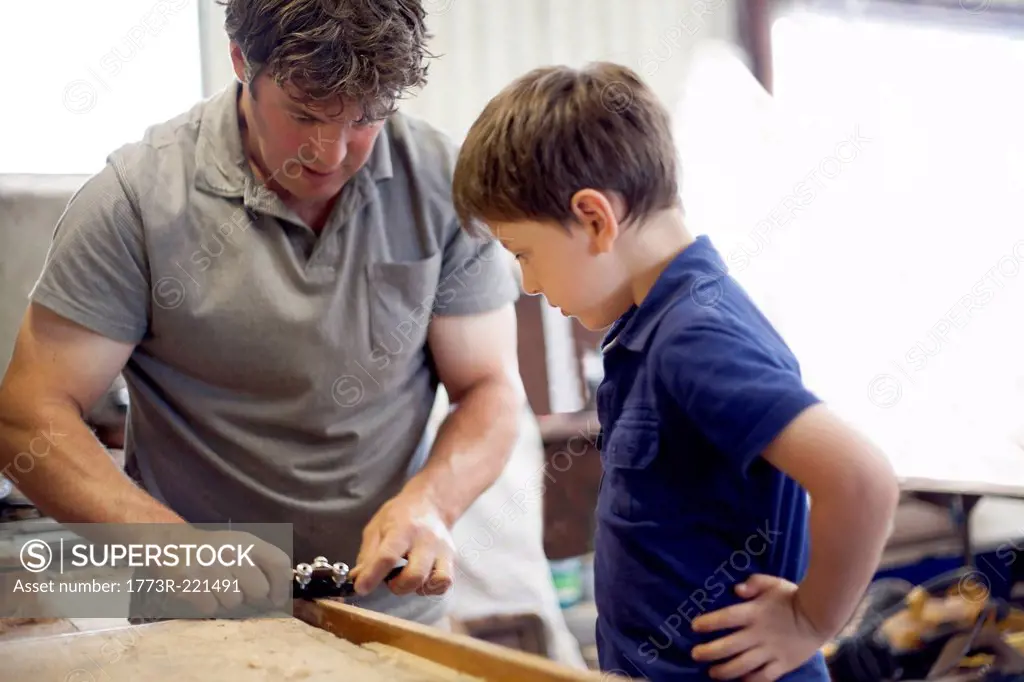 Father showing son carpentry in boat workshop