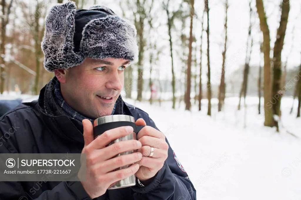 Mature man having hot drink outside in winter