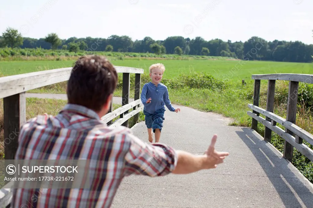 Boy running over wooden bridge towards dad