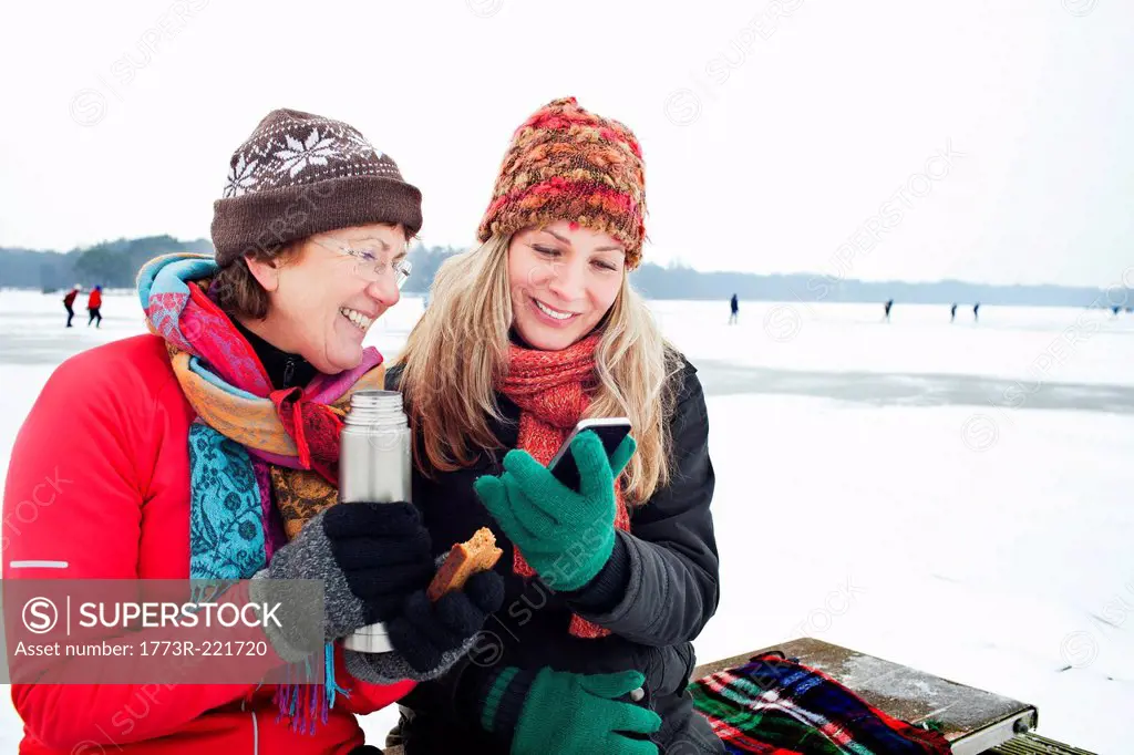 Women having hot drinking and looking at smartphone