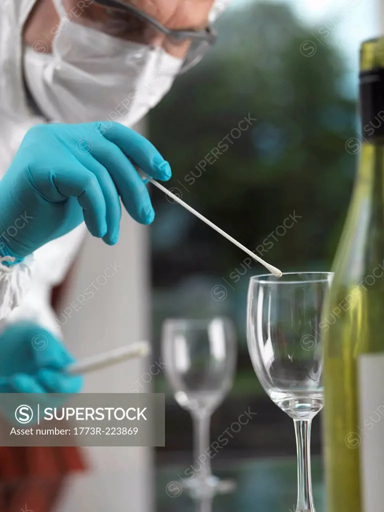 Forensic scientist using a DNA swab to take evidence from a glass at a scene of crime