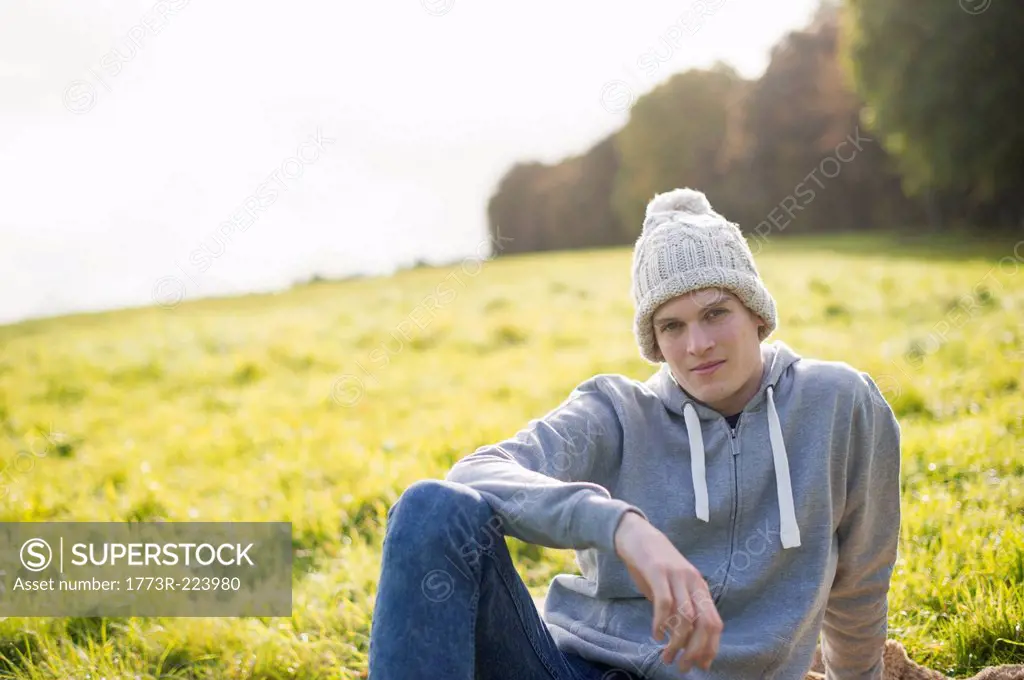 Portrait of young man sitting on grass wearing knit hat