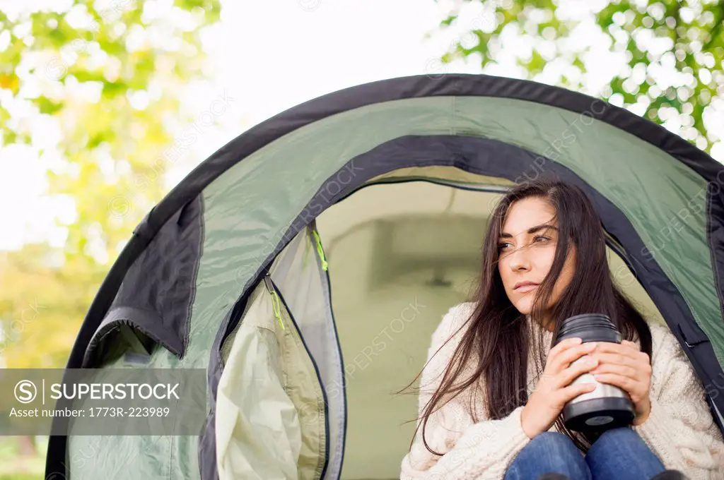 Young woman in tent holding flask