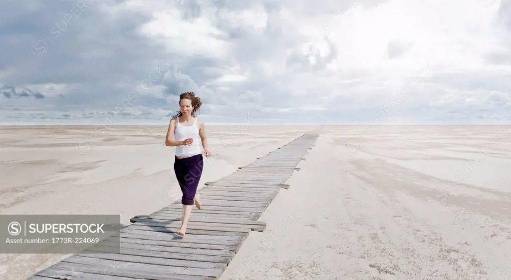 Woman running on boardwalk, Sankt Peter Ordings, Schleswig Holstein, Germany