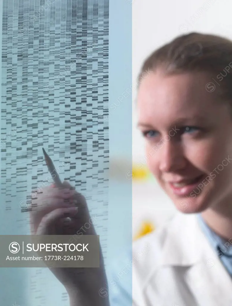 Female researcher examining DNA autoradiogram gel in laboratory